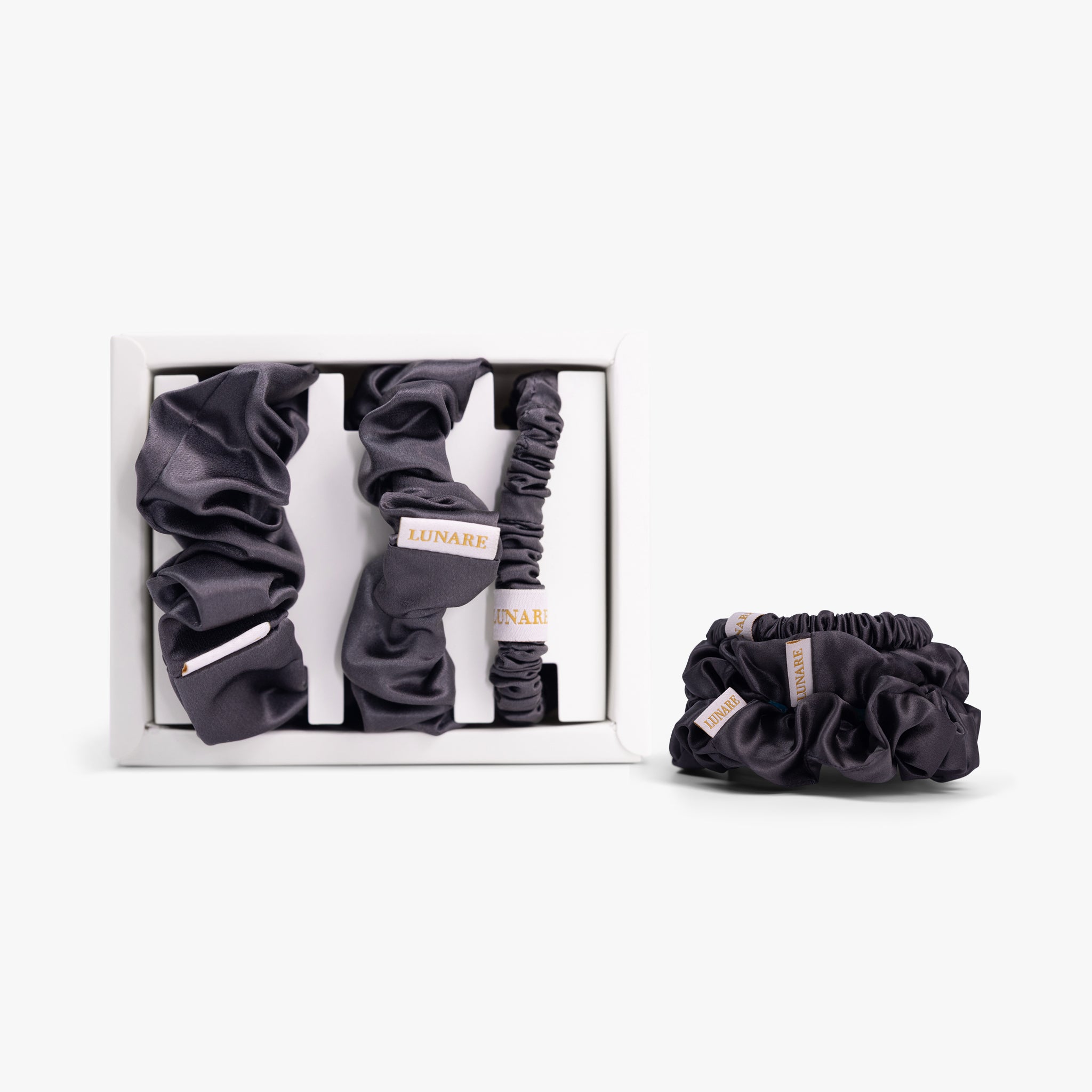 Dark grey silk scrunchies in open box with stacked set on white background
