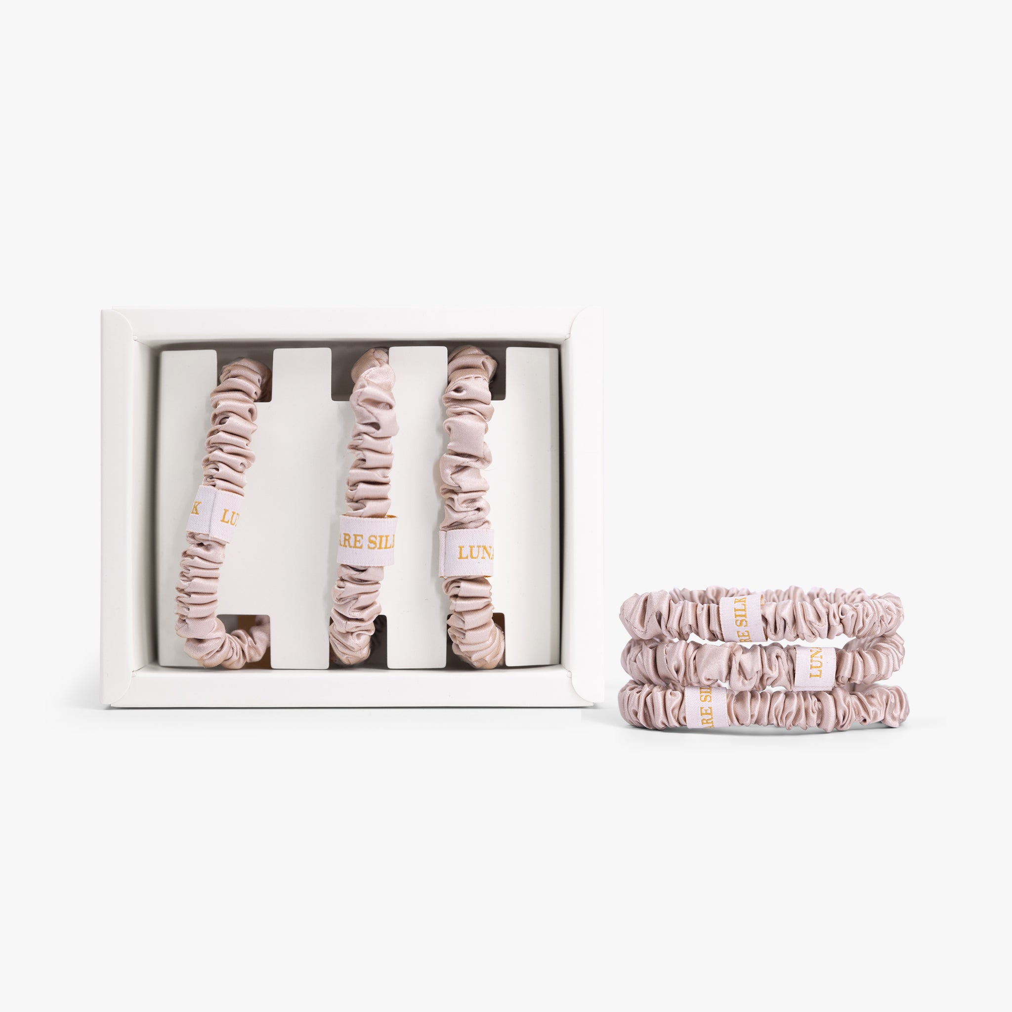 Set of champagne scrunchies with packaging on a white background