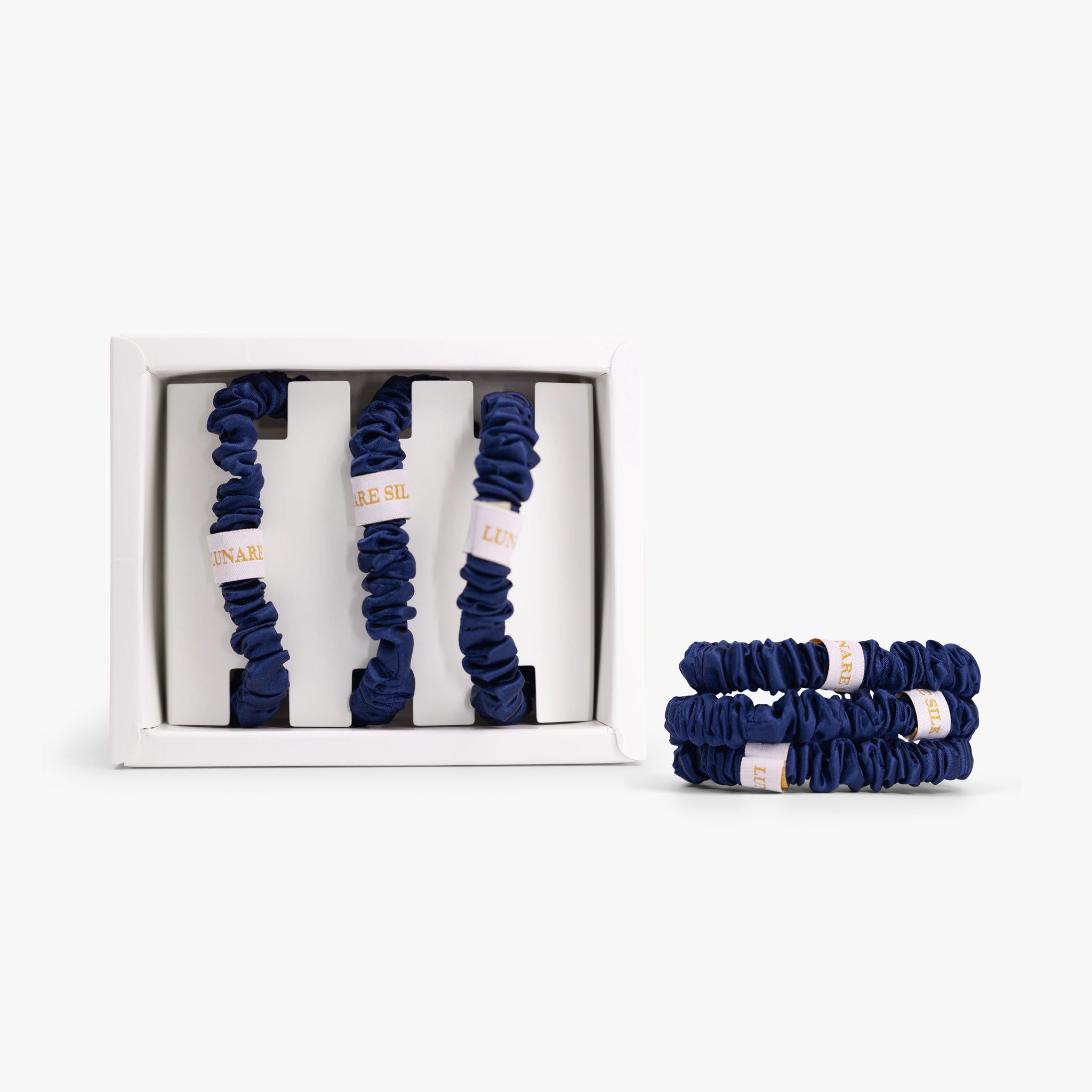Set of navy blue scrunchies with a white box on a white background
