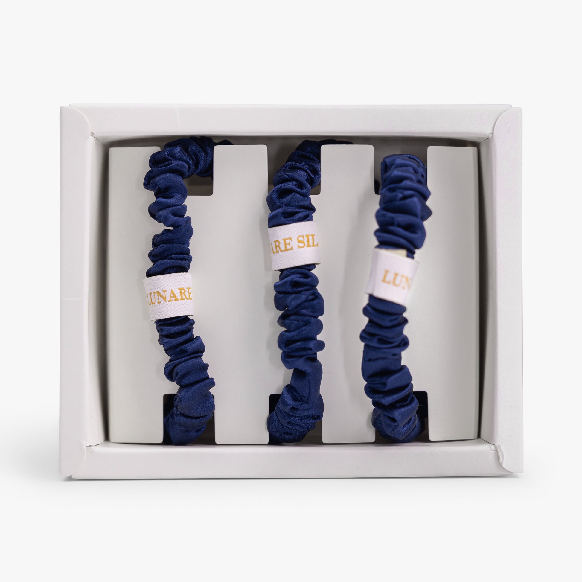 Set of three navy  blue scrunchies in a white box with LUNARE SILK branding.