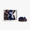 Dark neutral silk scrunchies in open box with stacked set on white background

