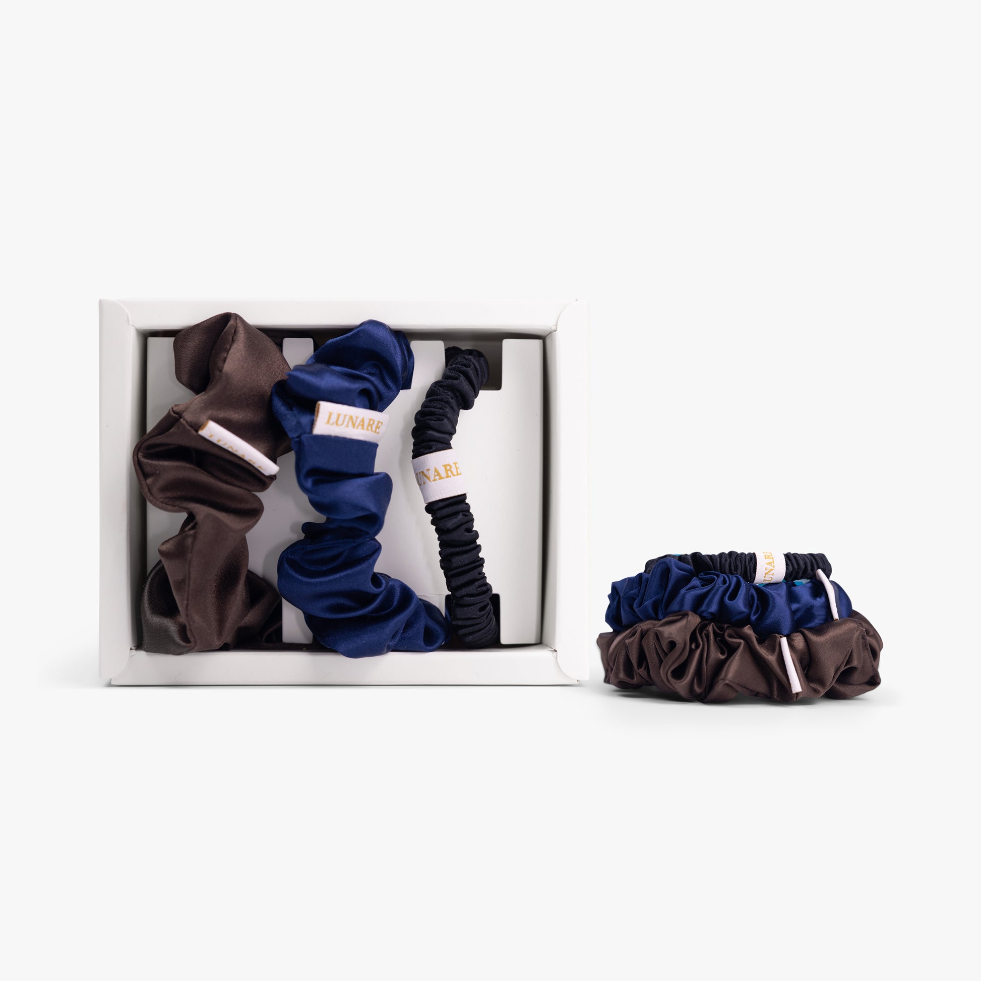 Dark neutral silk scrunchies in open box with stacked set on white background
