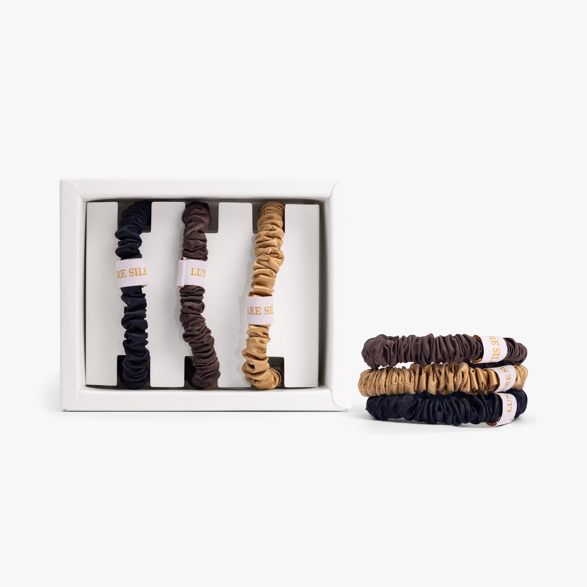 Set  of small hair ties in a box with additional hair ties displayed on a white background