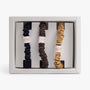 Set of three scrunchies in black, brown, and beige with visible brand name in a box.