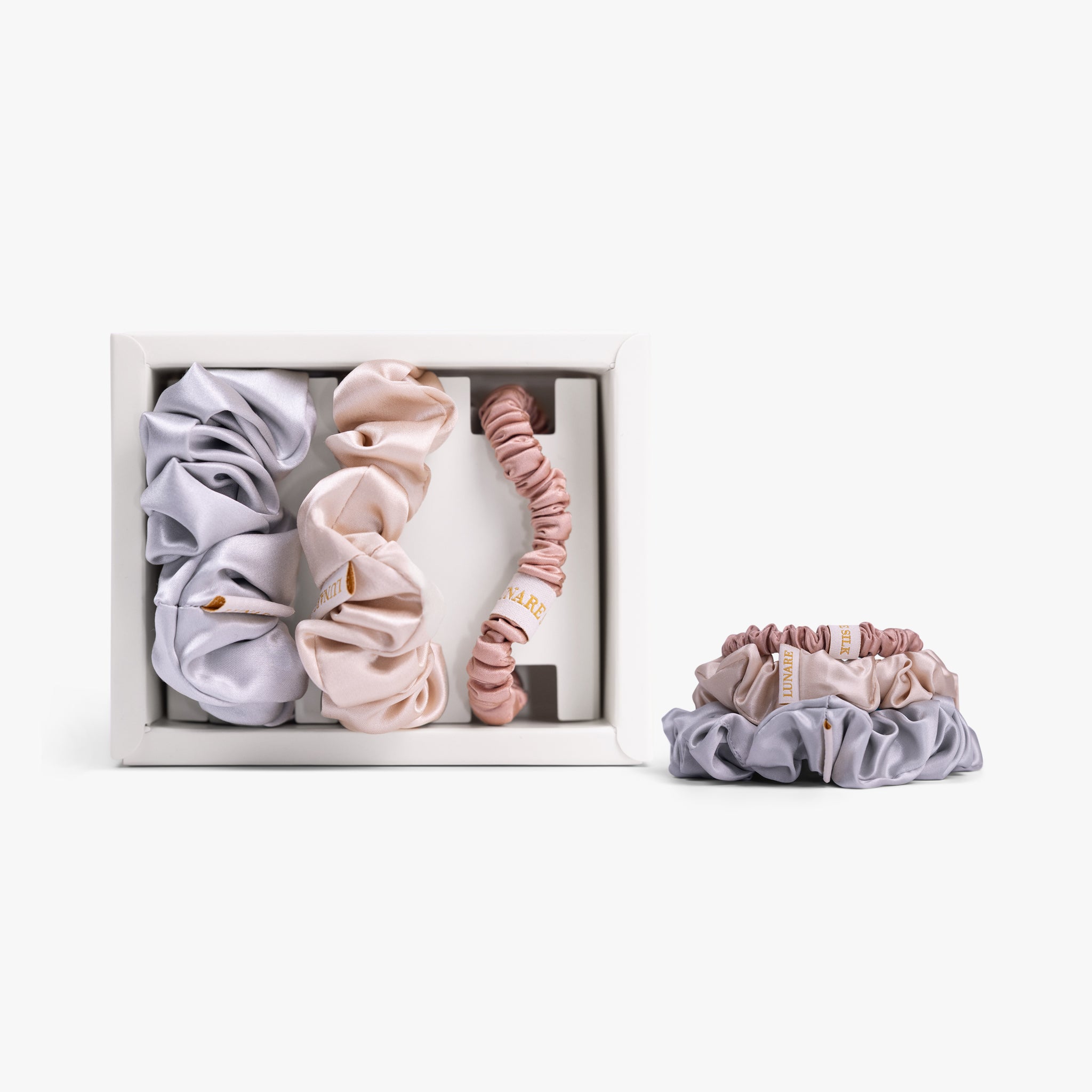 Soft neutral silk scrunchies in open box with stacked set on white background

