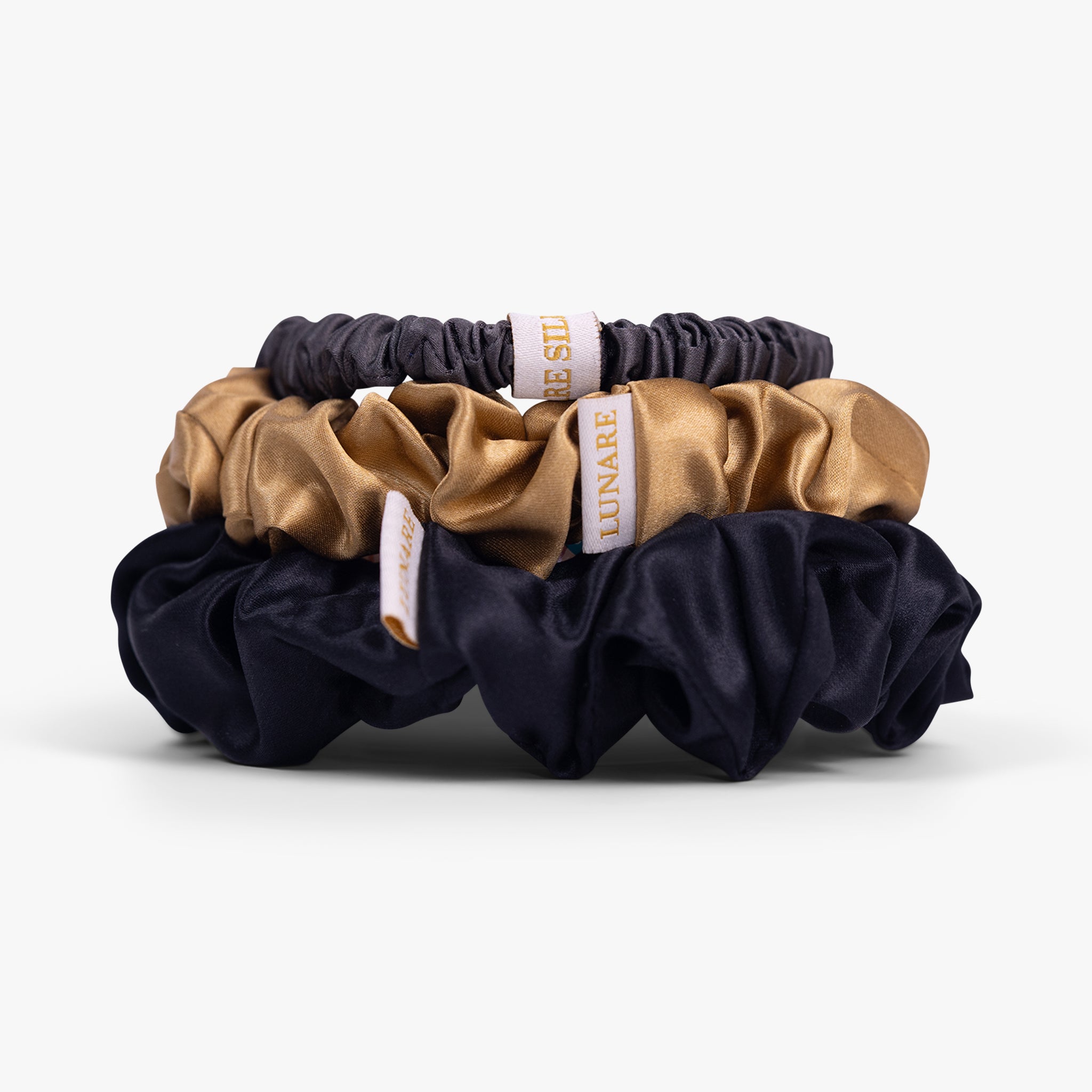 Classic neutral silk scrunchies stacked from large to small on white background
