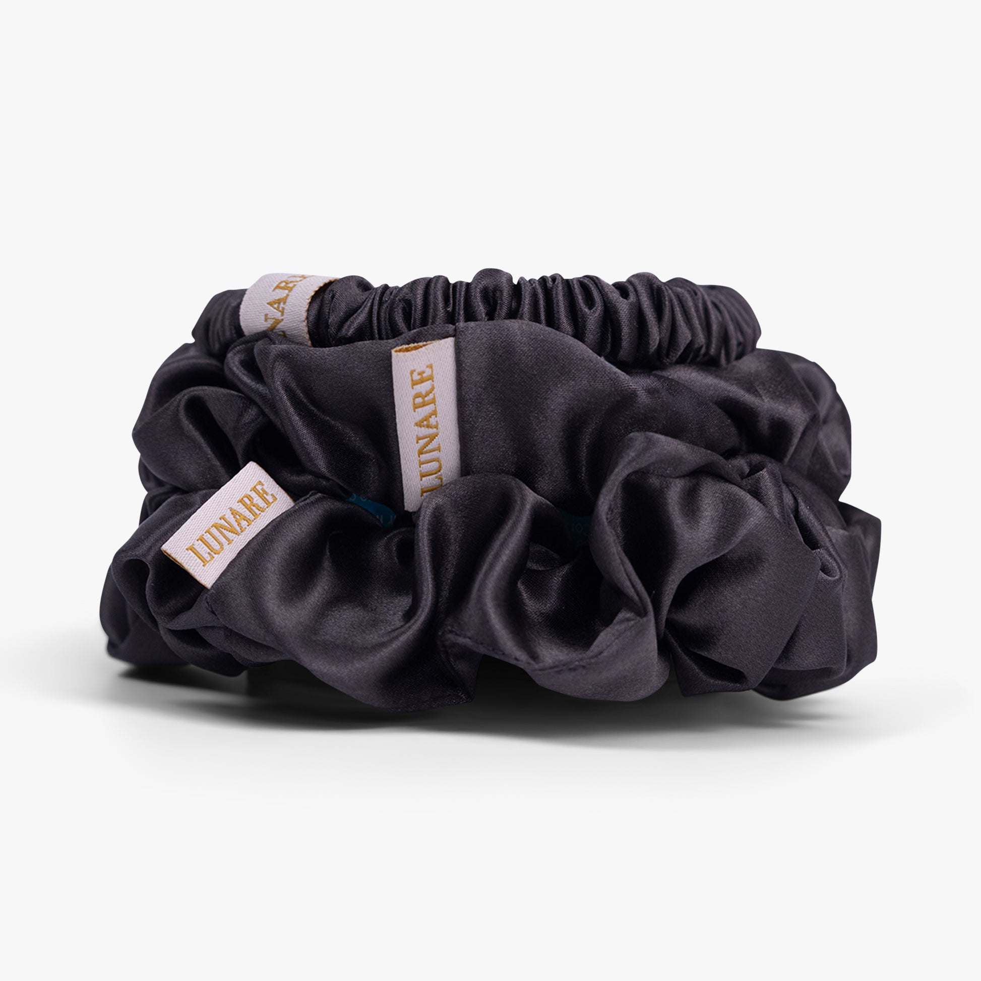 Dark grey silk scrunchies stacked from large to small on white background
