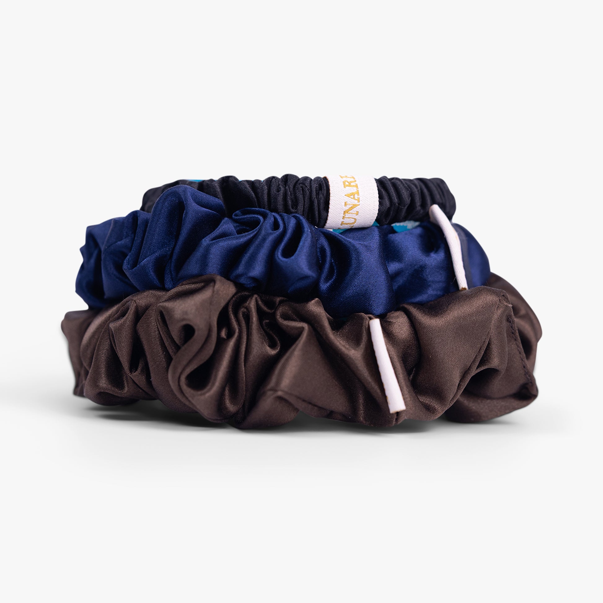 Dark neutral silk scrunchies stacked from large to small on white background
