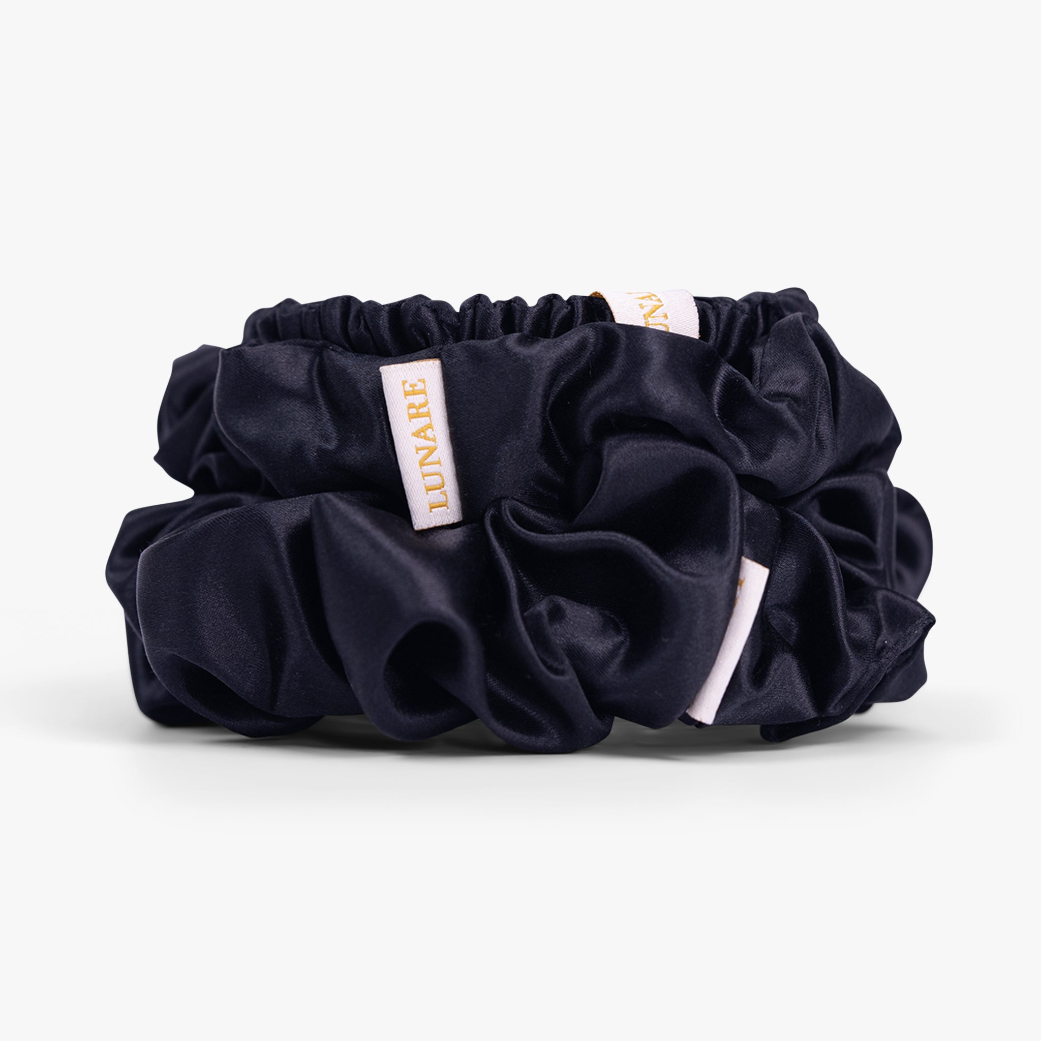 Black silk scrunchies stacked from large to small on white background
