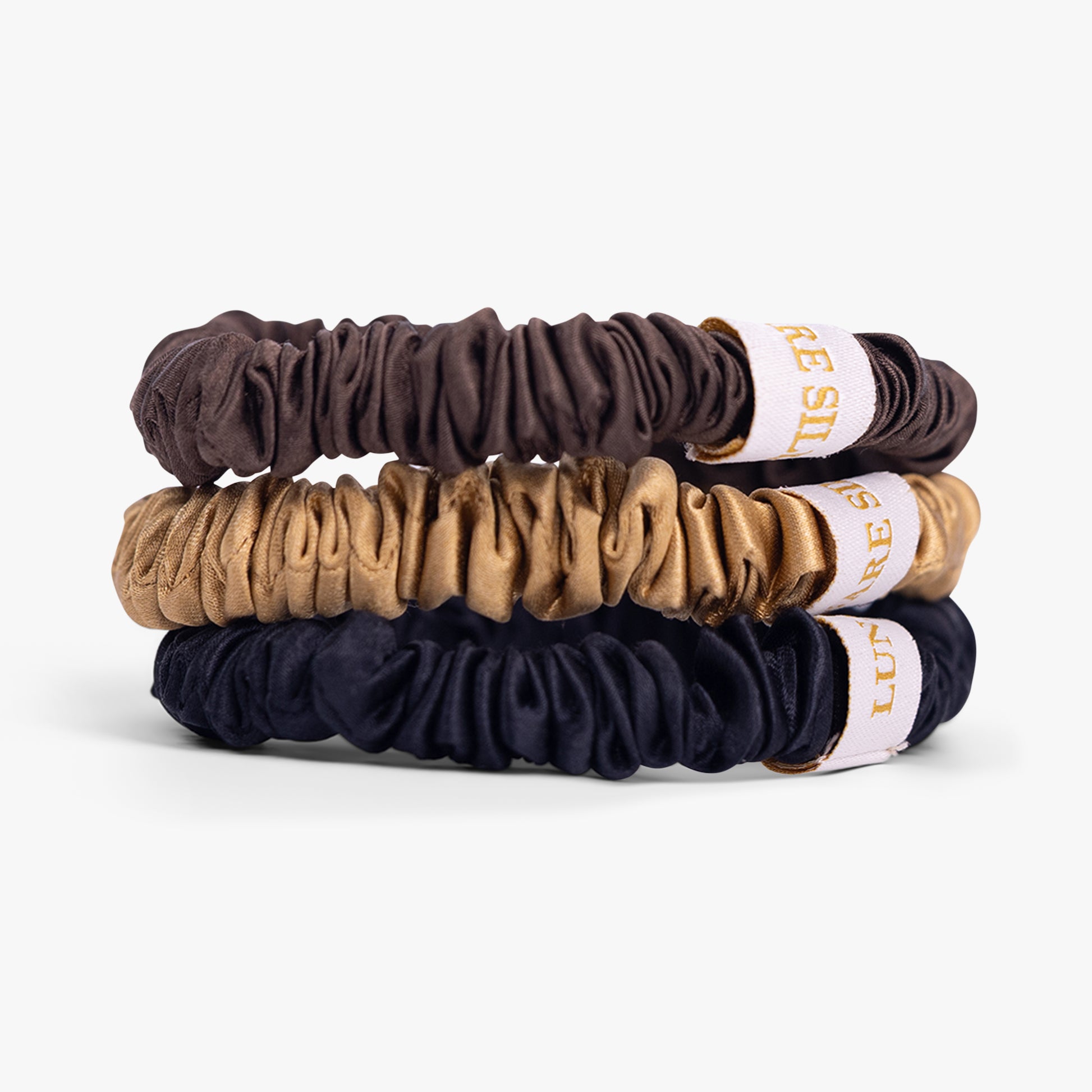 Three scrunchies in brown, beige, and navy on a white background