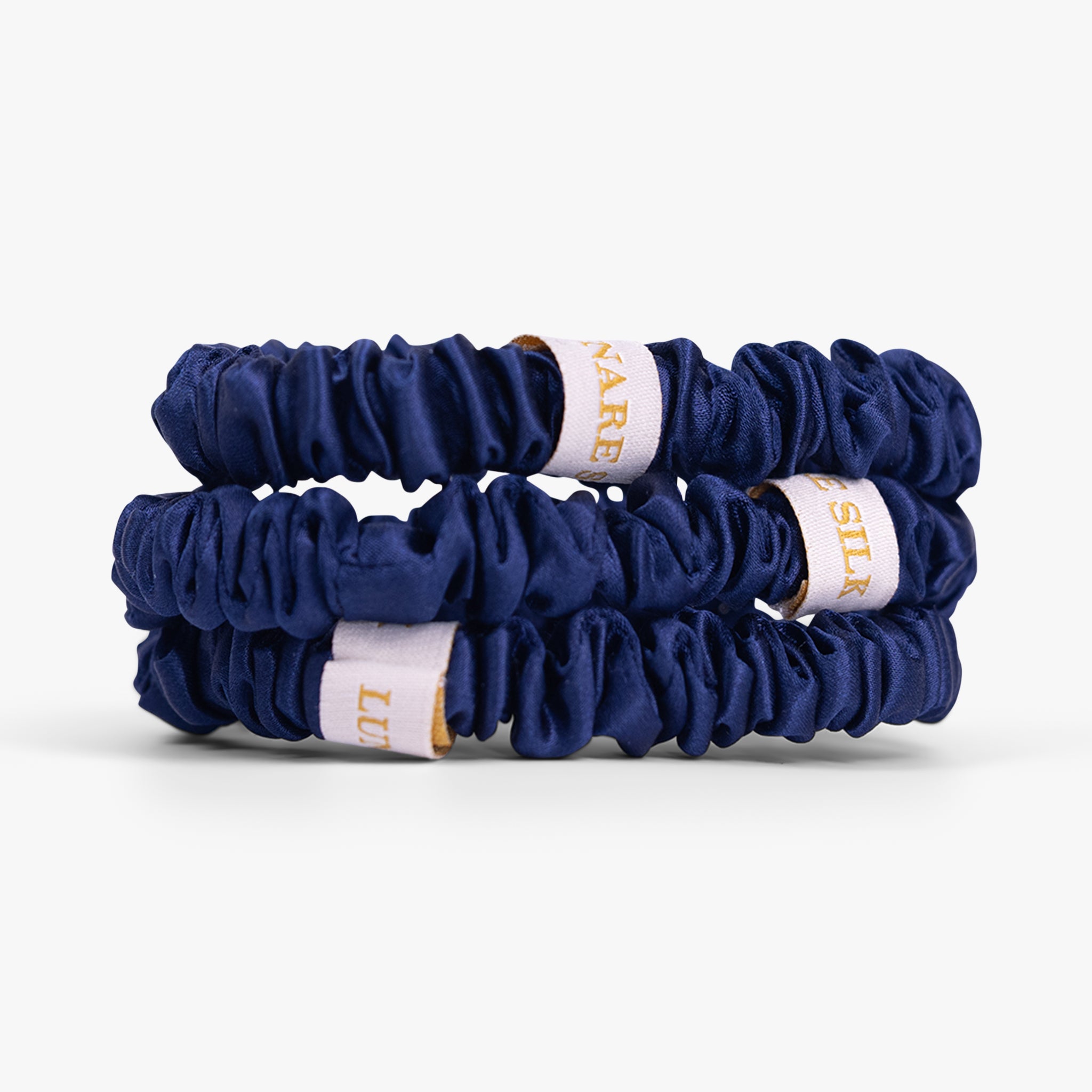 Two navy blue hair scrunchies with white labels on a white background