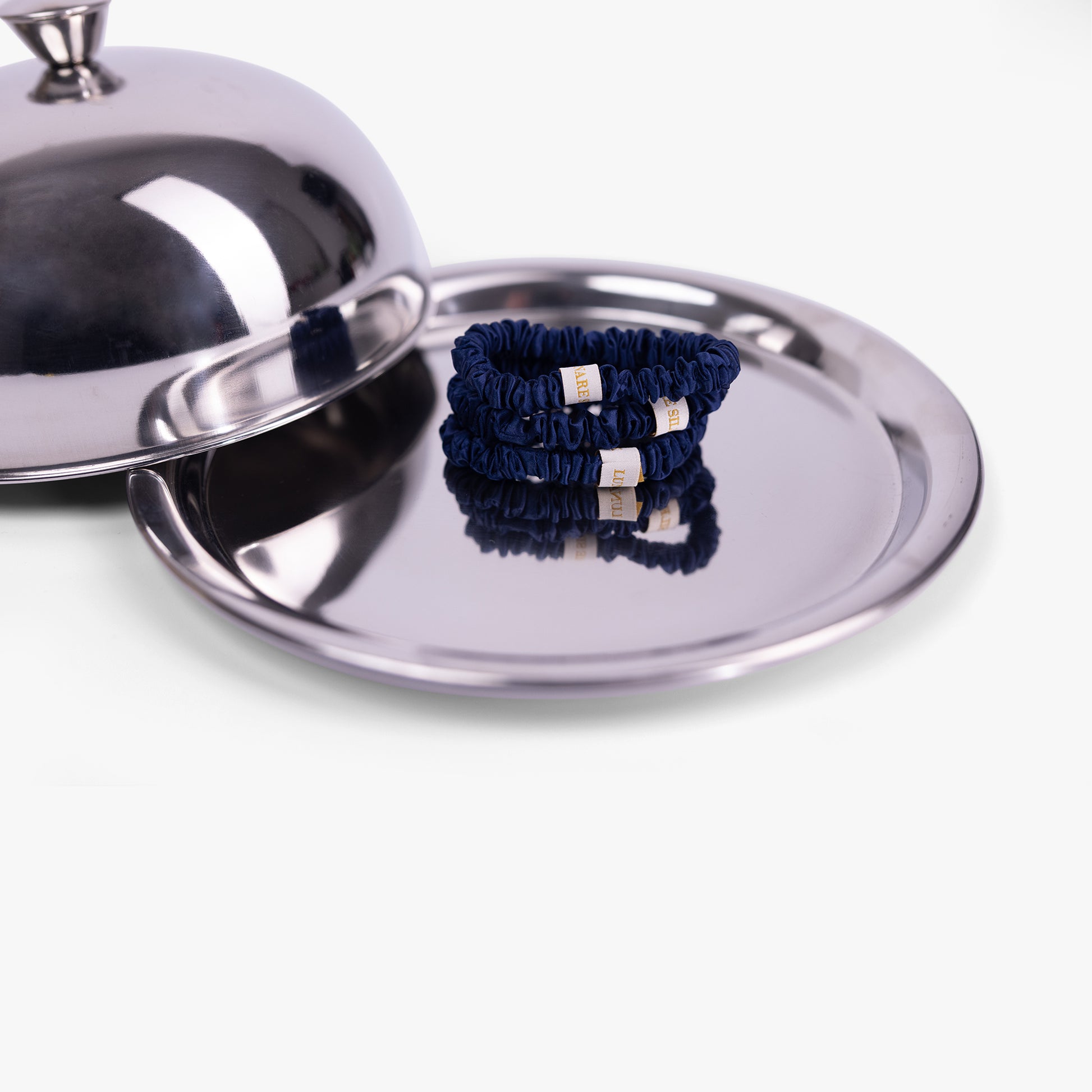 Navy blue hair ties with gold accents on a silver tray
