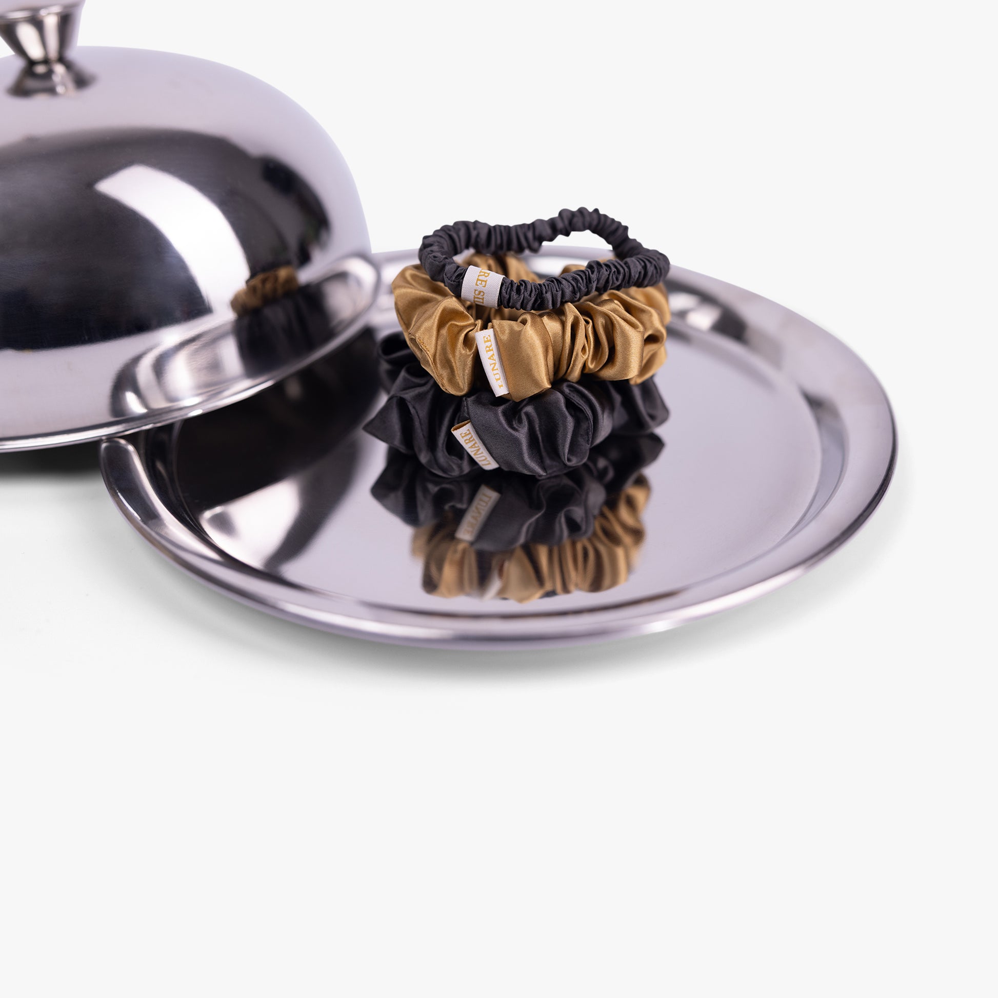 Warm contrast silk scrunchies displayed on silver tray
