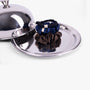 Dark neutral silk scrunchies on silver tray with lid
