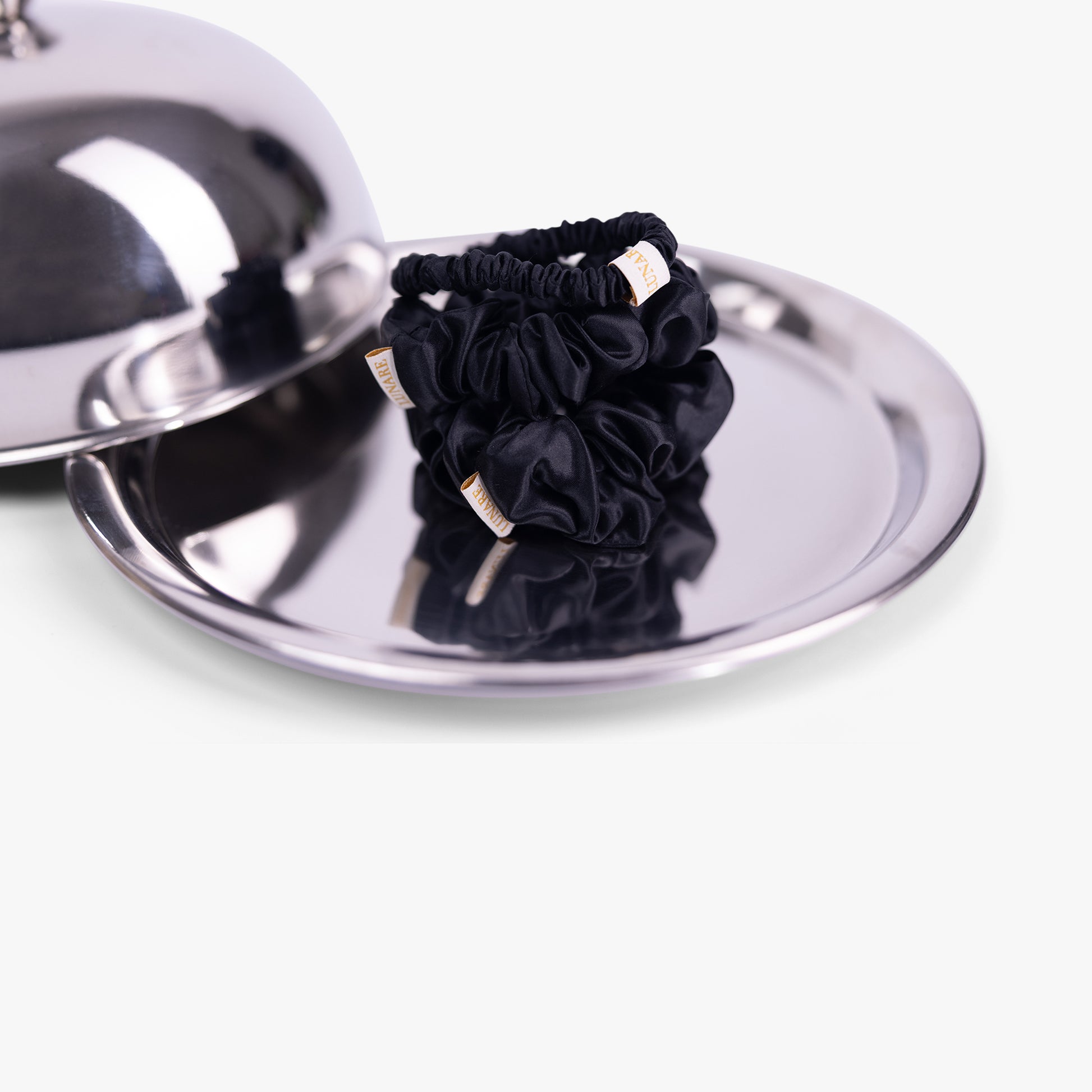 Black silk scrunchies on silver tray with lid
