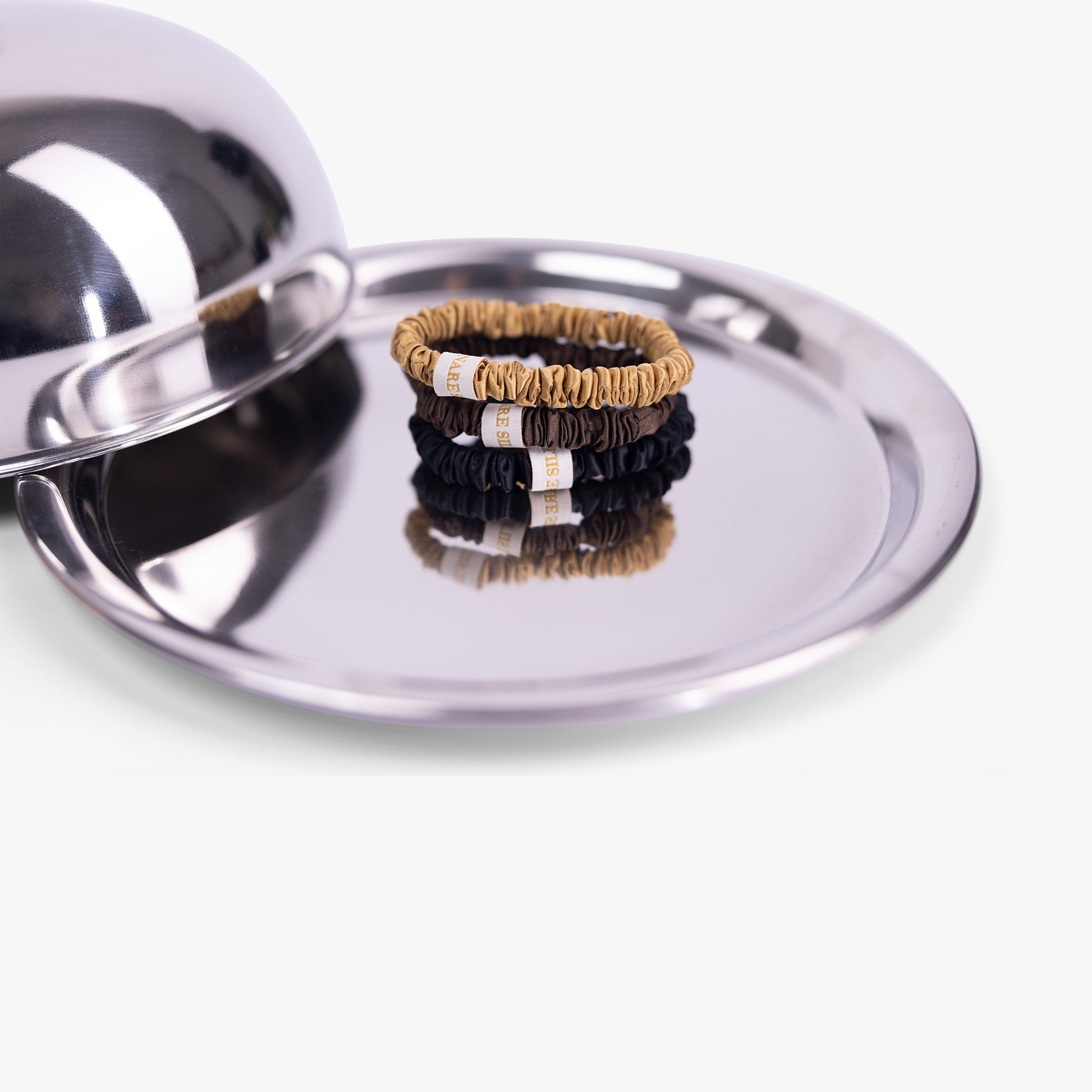 Set of hair ties on a metallic surface with a reflective lid.