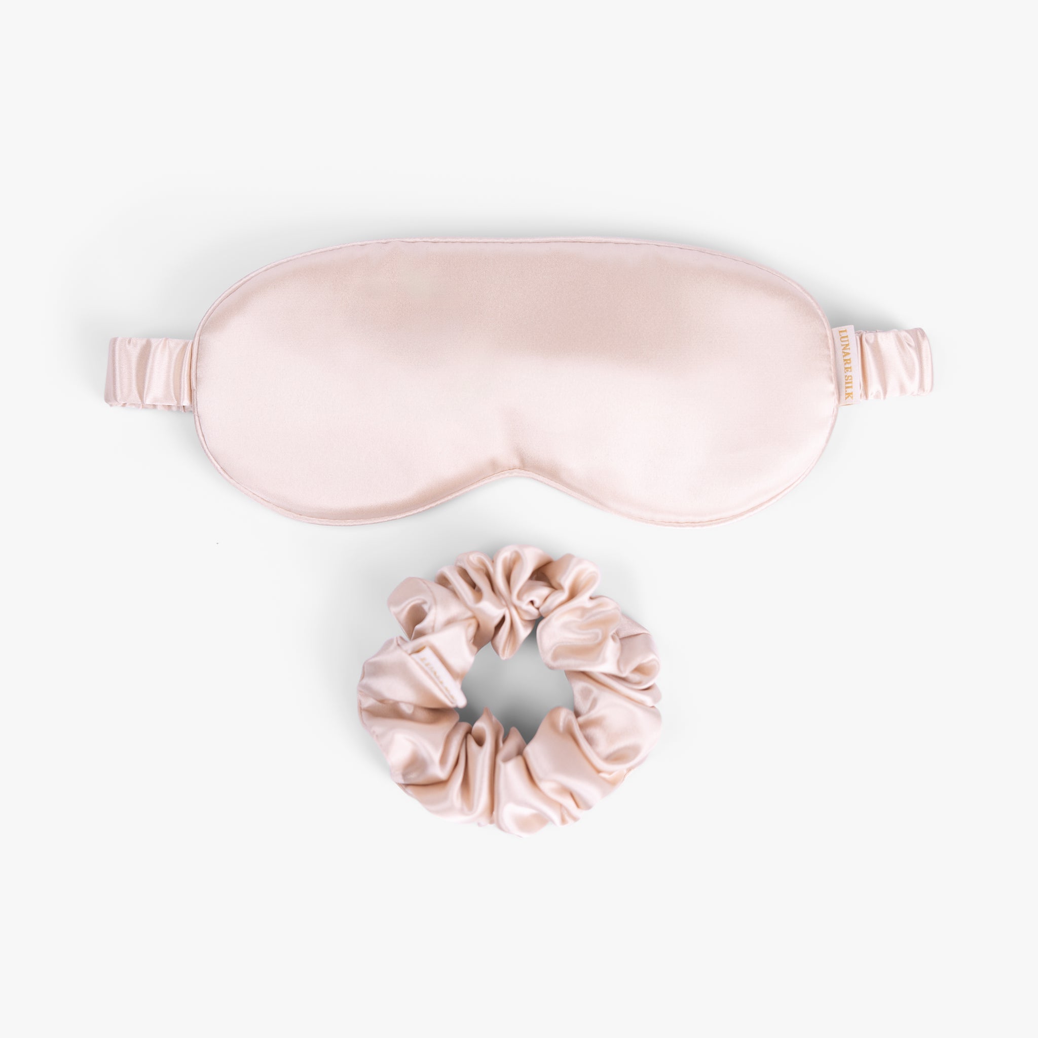 Rose gold care silk bundle with eye mask and scrunchie on white background
