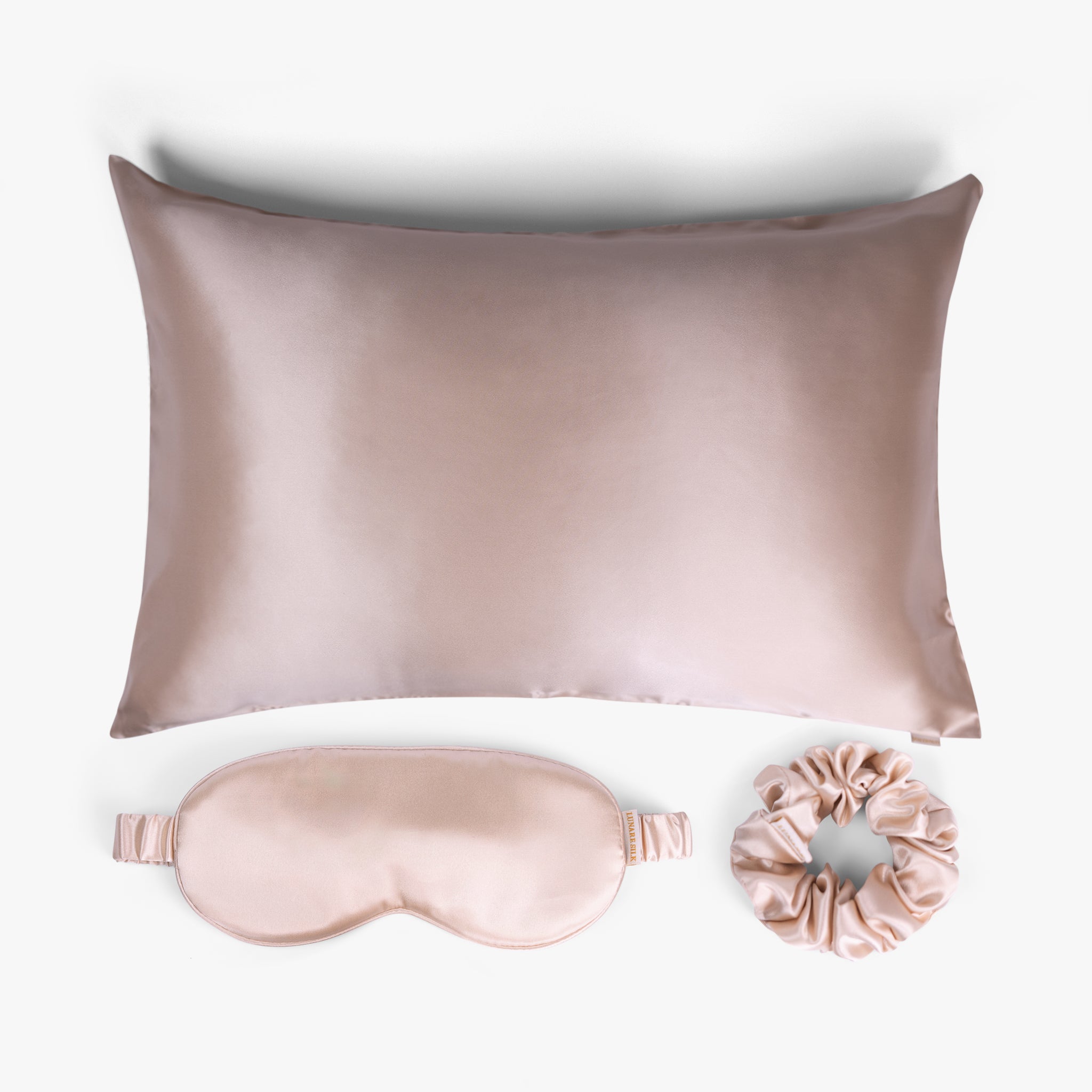 Champagne ritual silk bundle with pillowcase, eye mask and scrunchie on white background
