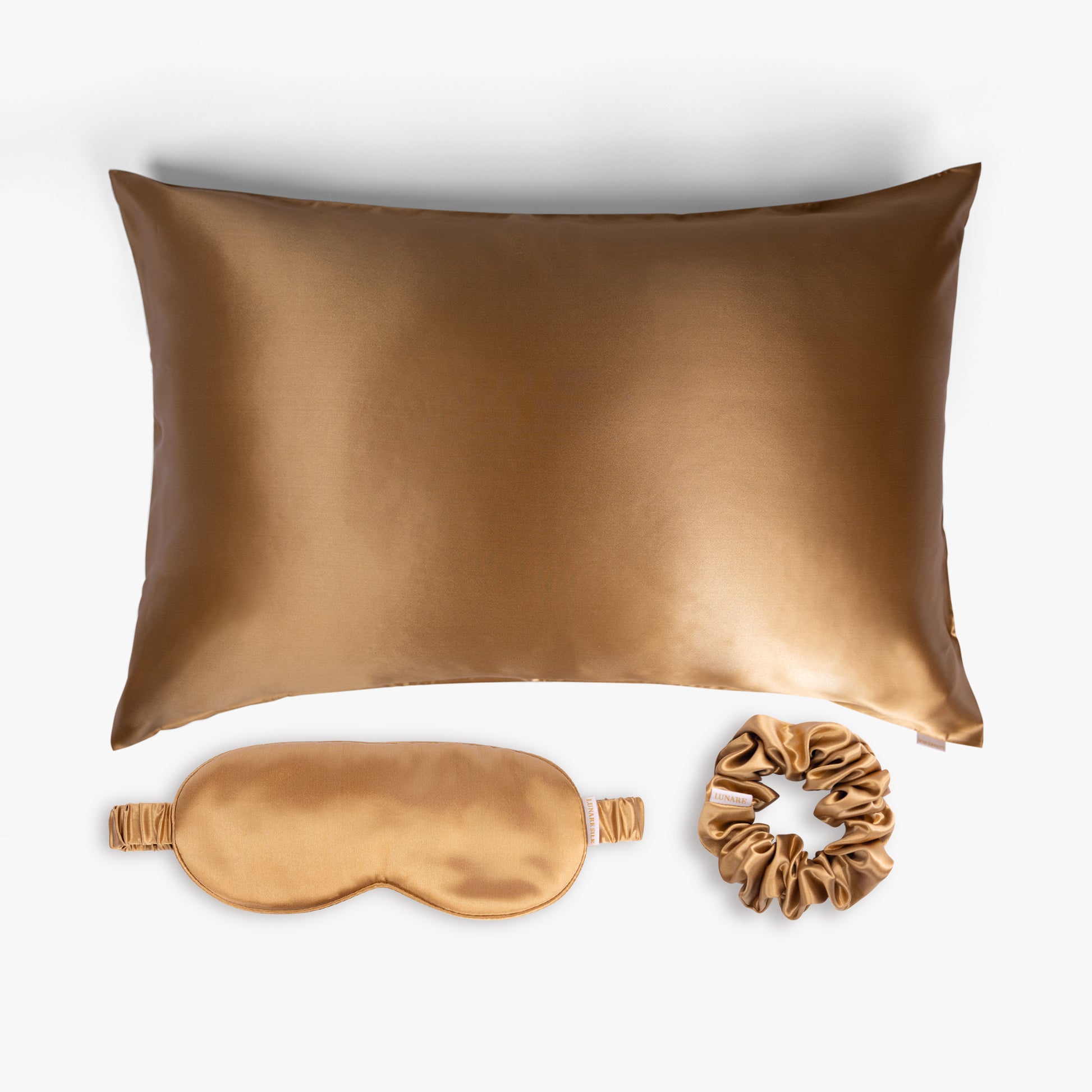 Amber gold ritual silk bundle with pillowcase, eye mask and scrunchie on white background

