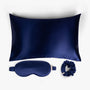 Navy blue ritual silk bundle with pillowcase, eye mask and scrunchie on white background
