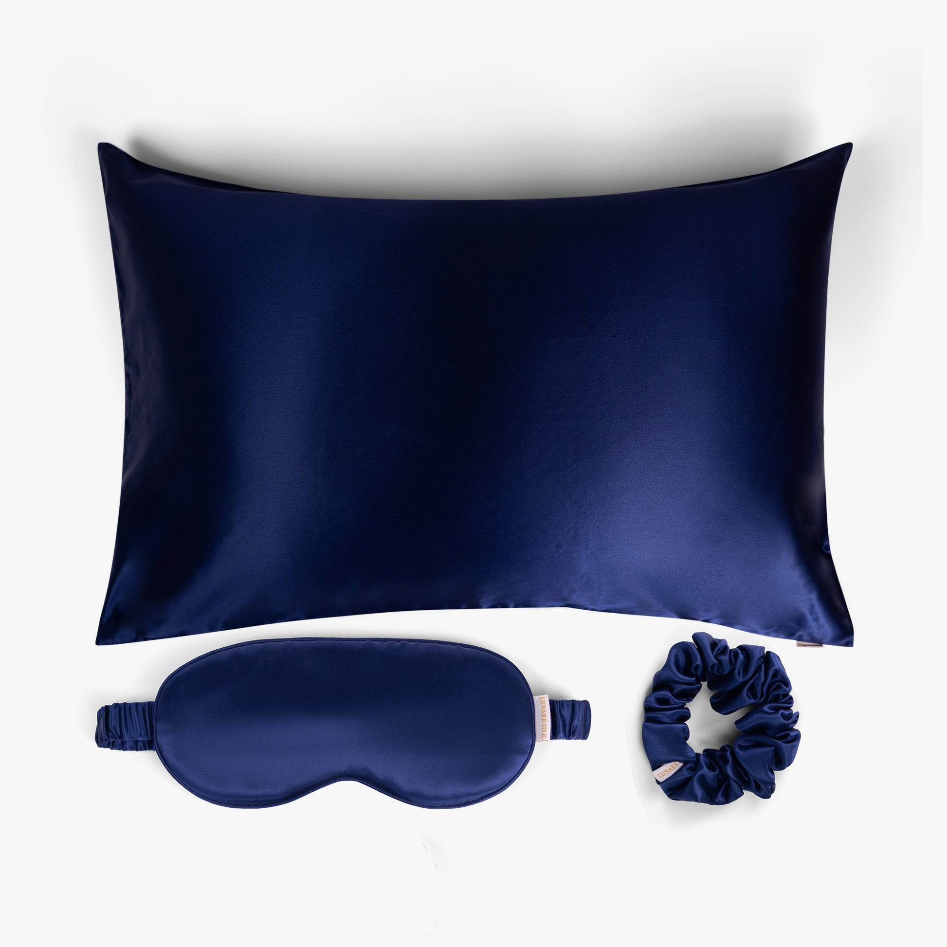 Navy blue ritual silk bundle with pillowcase, eye mask and scrunchie on white background
